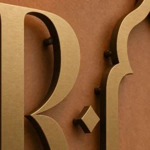 Détail de la matière et de la finition de Enseigne Riad en laiton.